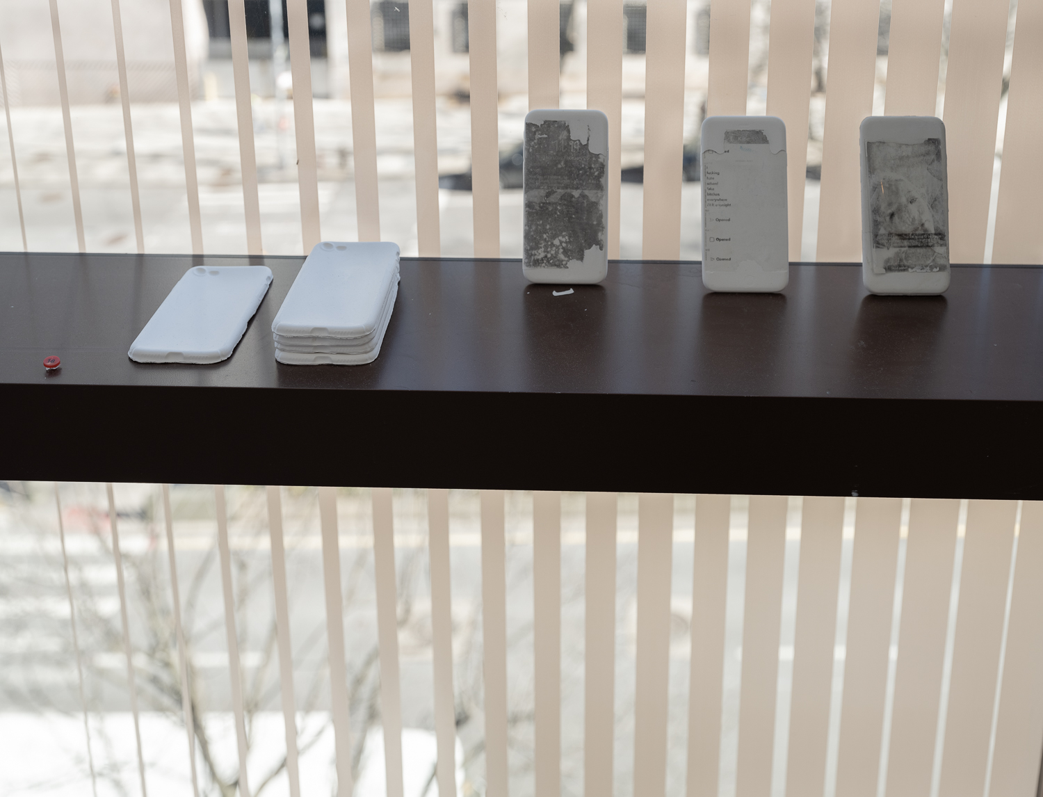 Five dummy iPhones are on display, with black-and-white screen renderings of the artist's memories